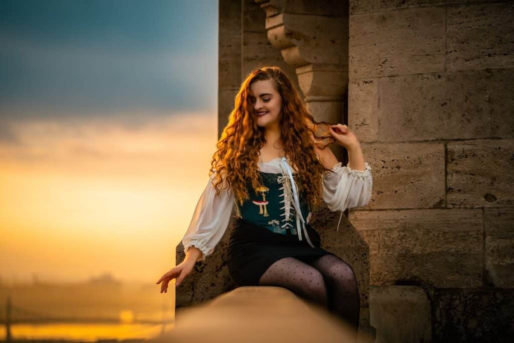 Red-haired girl in a corset sitting on a balcony at Buda Castle in Budapest, Hungary for a travel photoshoot