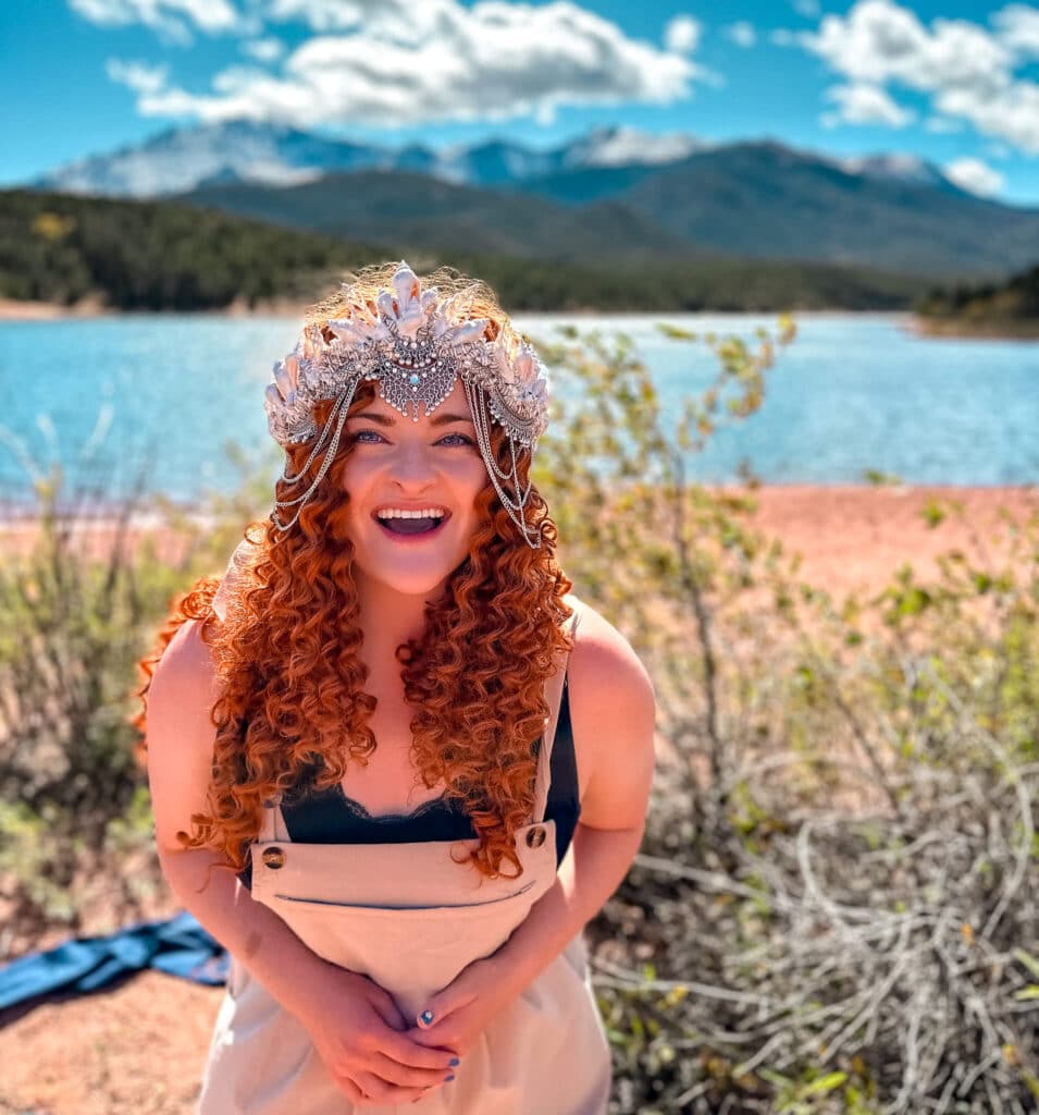 The Bucket List mermaid smiling in front of lake and mountains