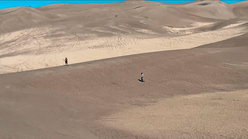 Two people trying to sandboard in the Great Sand Dunes