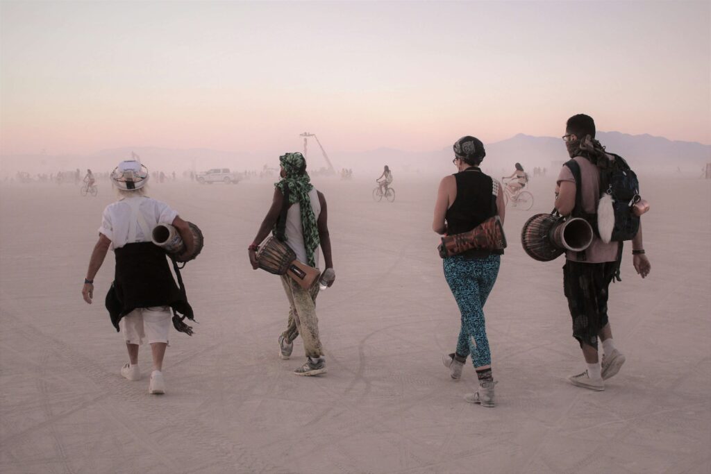 Four people walking towards Burning Man Festival in Nevada for their August Bucket List