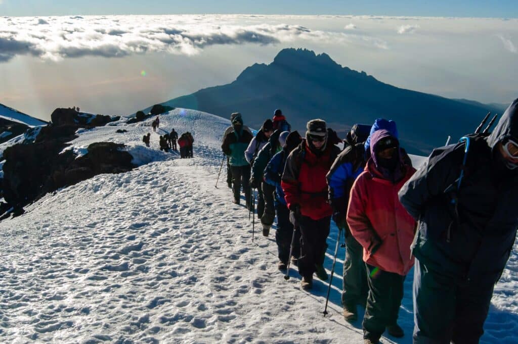 A line of people hiking Mt. Kilimanjaro, Uhuru Peak. Hiking for their August Bucket list.