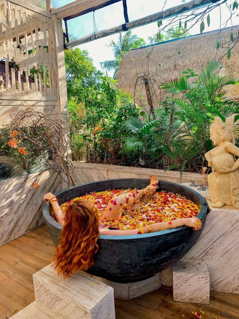 Red haired girl in a flower bath in the Gili Islands in Bali