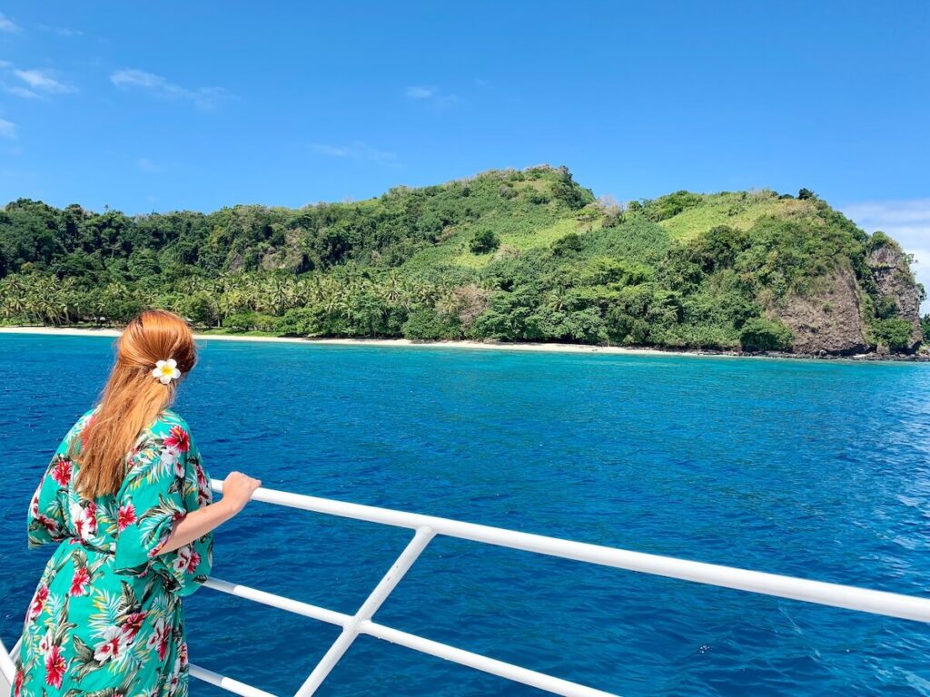 Red-haired girl looking over edge of a boat at Fiji water in the Yasawa Islands