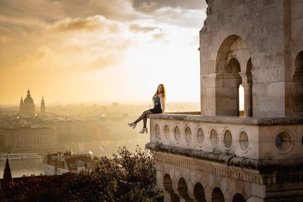 Girl sitting on edge of balcony in Budapest for a photoshoot