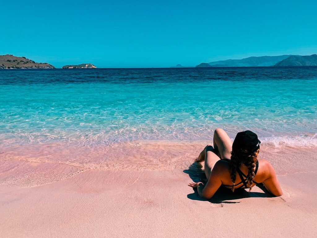 Girl laying on pink beach in the Komodo Islands