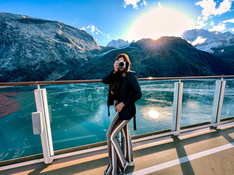 Girl in striped pants in Alaska holding up a camera taking a picture at Glacier Bay