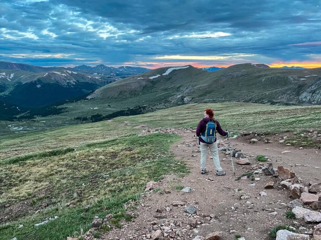 A hiker posing in front of a mountain and a sunset in Colorado