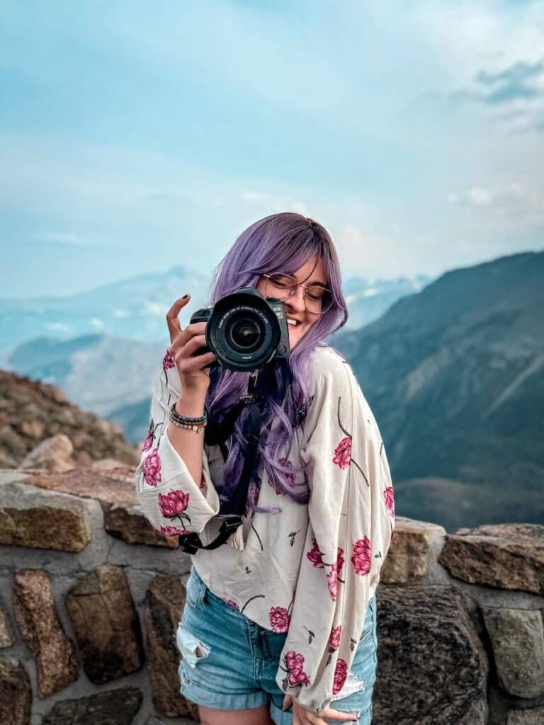 a girl with purple hair holding a camera in rocky mountain national park