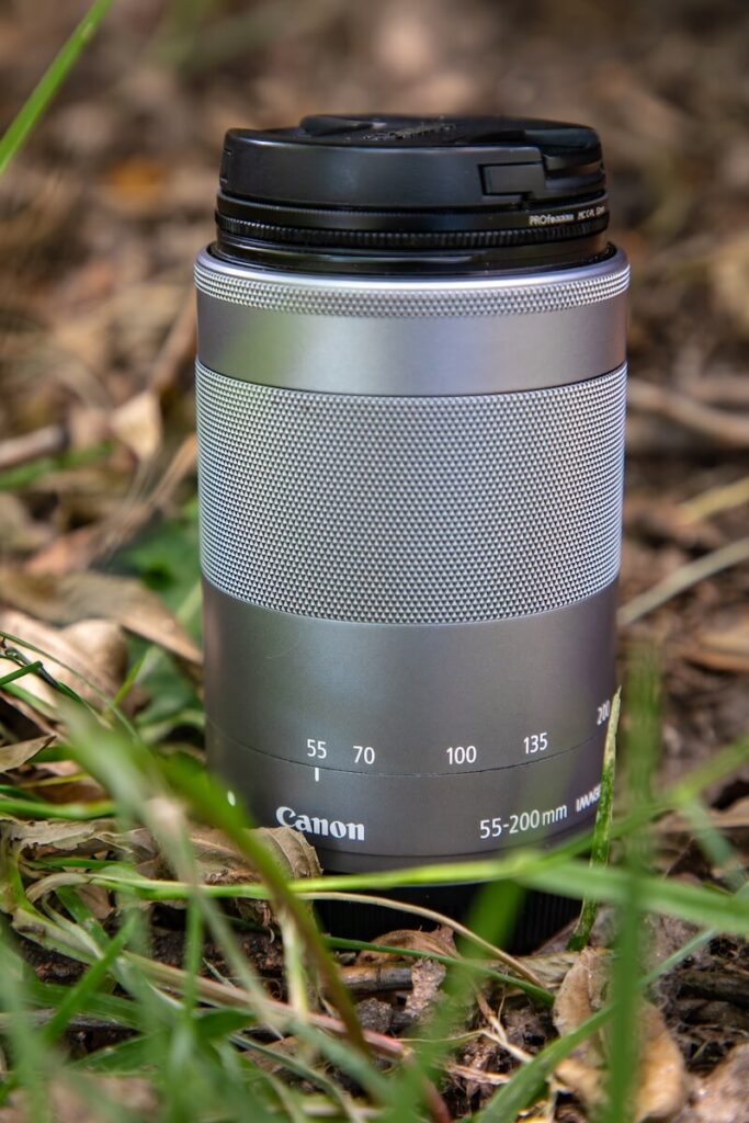 A 70-200 mm lens sitting in the grass discussing the best lens for travel photography