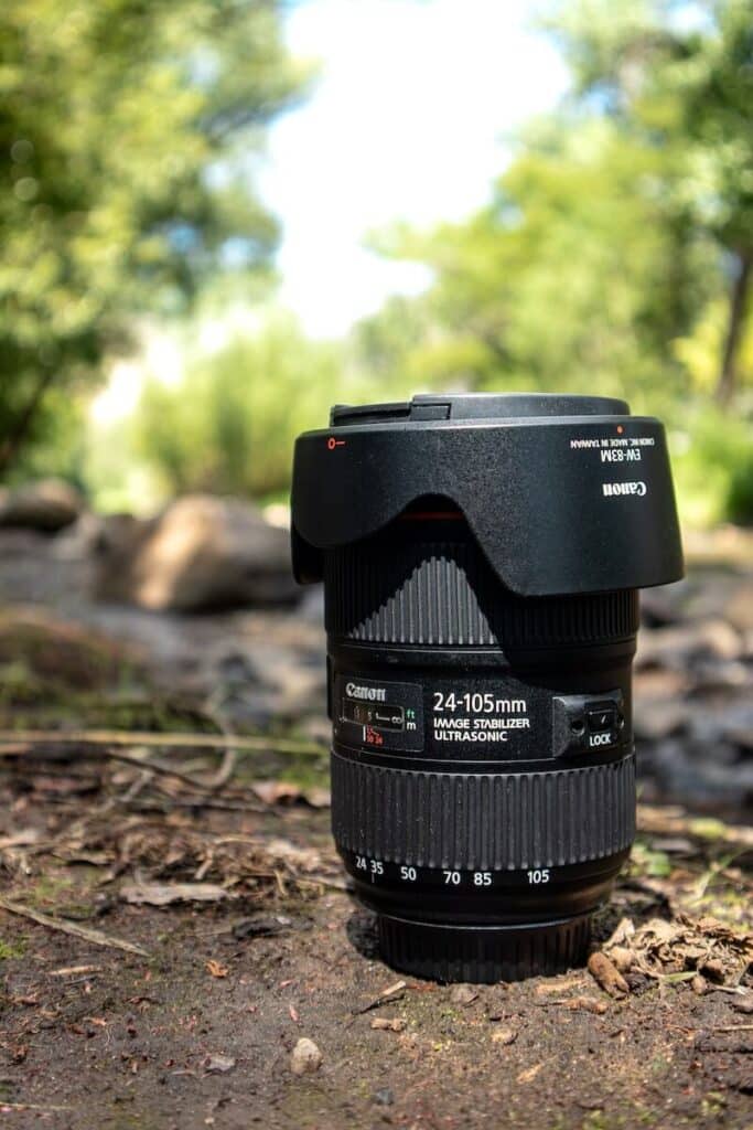 A 45-105 mm lens sitting in the grass discussing the best lens for travel photography