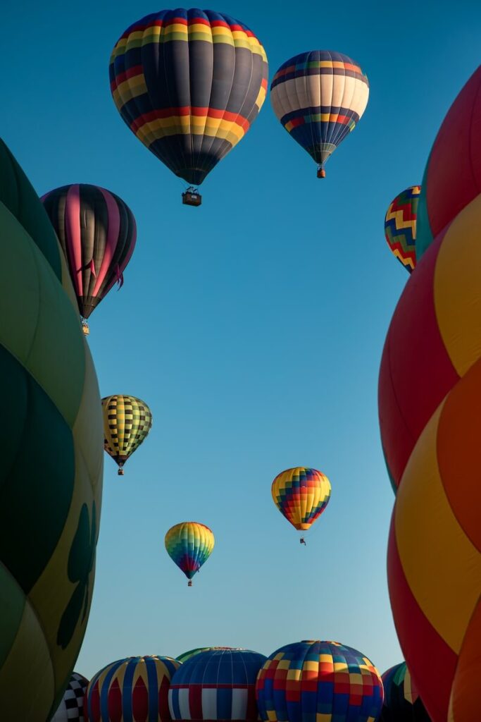 Balloons in the distance while framed with two hot air balloons taking off from the ground at the Balloon Festival in New Mexico