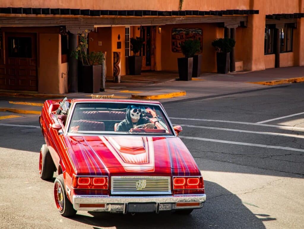 A red car turning in Sante Fe with a skeleton driver for Day of the Dead.