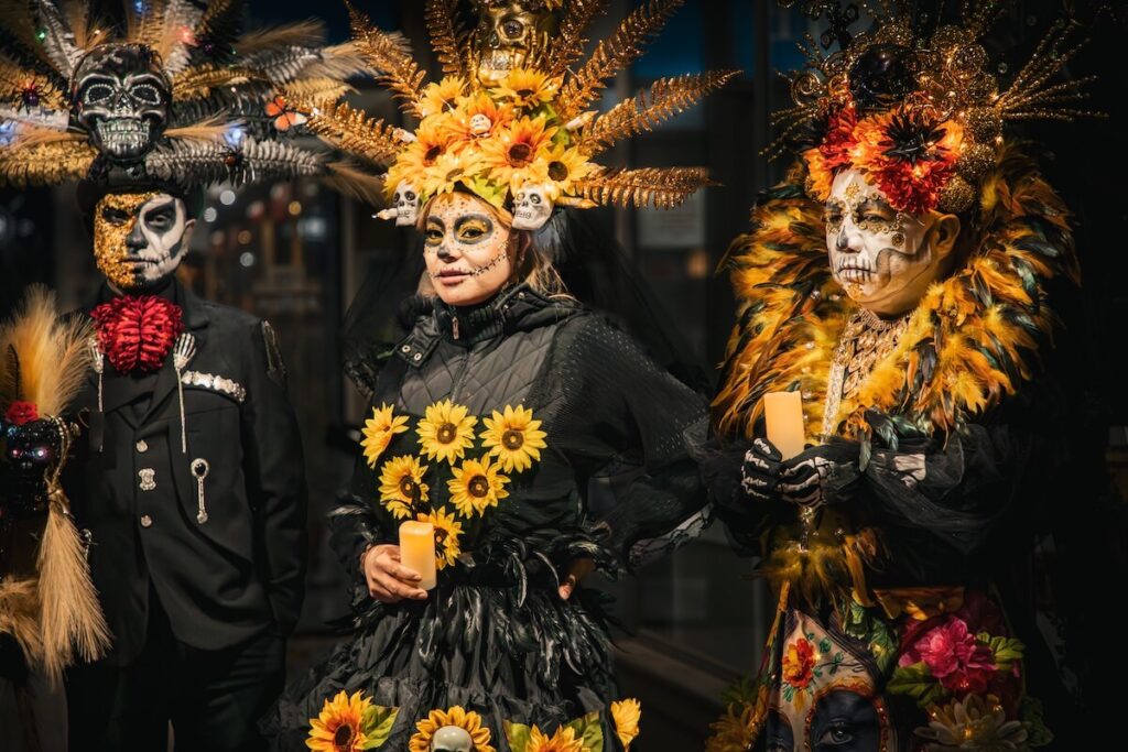 Three locals in skeleton outfits, honoring the Dias De Los Muertos tradition in New Mexico