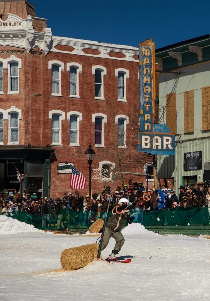 A skier trying to grab small orange rings will being pulled by a horse in skijoring