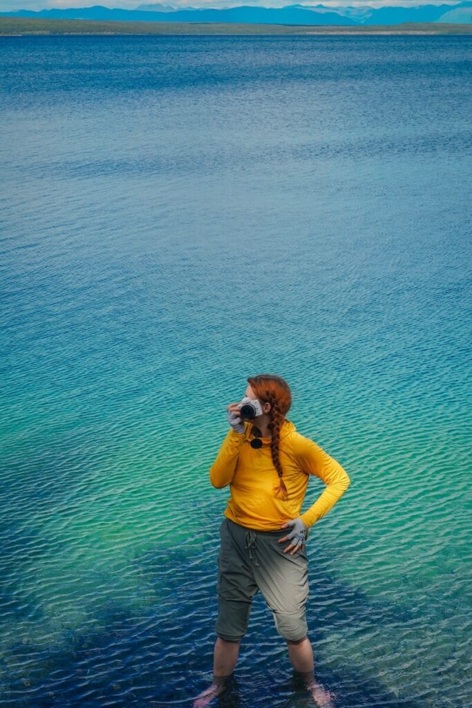 A girl in a yellow sun shirt standing in Kathleen Lake (Canada) with her small white camera.